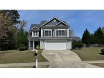 Charming two-story home showcasing a manicured lawn, blue siding, and attached two-car garage at 404 Braxman Ln, Holly Springs, NC 27540