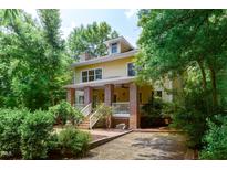 Inviting yellow two-story home boasts a brick porch, lush landscaping, and a welcoming entrance at 407A Hillsborough St, Chapel Hill, NC 27514