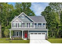 Charming two-story home showcasing a red front door, a two-car garage, and beautiful architectural details at 557 Freedom Trail Dr, Willow Springs, NC 27592