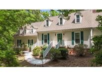 Charming home featuring dormer windows, lush landscaping, and inviting walkway leading to the front entrance at 63 Tally Ho Dr, Selma, NC 27576