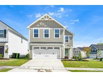 Charming two-story home with a two-car garage, sage green exterior, and manicured lawn at 653 Corvair Ln, Wendell, NC 27591