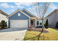 Charming blue single-story home featuring an attached garage, well-manicured lawn, and beautiful landscaping under a bright sky at 1247 Magic Hollow Rd, Durham, NC 27713