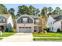 Charming two-story home with a brick and gray exterior, a well-manicured lawn, and an attached two-car garage at 1301 Elliott Ridge Ln, Morrisville, NC 27560