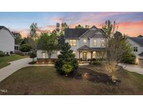 Stunning two-story home featuring manicured lawns and mature trees at sunset at 240 Swann Trl, Clayton, NC 27527