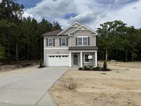 Charming two-story home featuring a two-car garage, stone accents, and a covered front porch in a wooded area at 4012 Kingcraig Ln, Zebulon, NC 27597