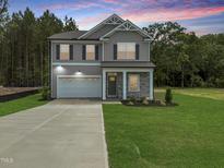 Beautiful two-story home with gray siding, stone accents, attached garage, and well-manicured lawn at 4012 Kingcraig Ln, Zebulon, NC 27597