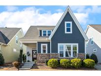 Charming two-story home featuring stone accents and a well-manicured front yard with green shrubbery at 405 Daisy Grove Ln, Holly Springs, NC 27540