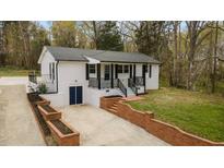 Beautifully renovated exterior of home featuring a brick retaining wall and covered front porch at 4509 Alamance Baptist Church Loop, Burlington, NC 27215