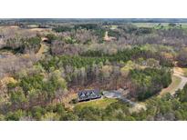 Stunning aerial view of modern home nestled in a lush, wooded landscape with driveway and ample parking at 90 Ferncrest Ct, Roxboro, NC 27574