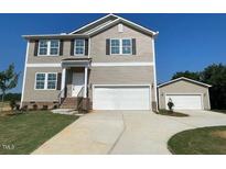 Two-story home with tan siding, dark shutters, attached two-car garage, and an additional detached garage at 15 Atherton Circle, Angier, NC 27501