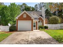 Charming brick and vinyl home featuring an attached garage, manicured lawn and mature trees at 200 Adefield Ln, Holly Springs, NC 27540