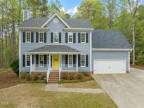 Charming two-story home with gray siding, black shutters, attached two car garage, and a bright yellow front door at 2032 Stoneglen Ln, Raleigh, NC 27603