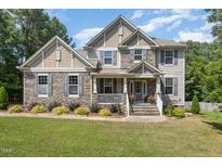 Charming two-story home showcasing a stone and shingle facade, complemented by a well-manicured lawn and mature trees at 45 Pebble Creek Dr, Franklinton, NC 27525