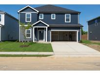 Two-story home featuring a two-car garage, well-maintained lawn, and classic siding against a backdrop of a bright blue sky at 601 White Birch Ln, Angier, NC 27501