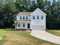 Charming two-story home with a classic white exterior, attached garage, and a well-maintained lawn and landscaping at 61 Atherton Circle, Angier, NC 27501
