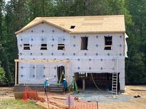 New two-story home featuring pre-construction with building materials and exposed beams in a wooded area at 62 Atherton Circle, Angier, NC 27501