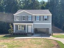 Charming two-story home with a covered front porch, attached two-car garage, and well-maintained lawn at 62 Atherton Circle, Angier, NC 27501