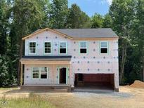 Two-story home with a two-car garage and a covered front porch, surrounded by lush trees at 62 Atherton Circle, Angier, NC 27501