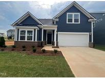 Charming single-Gathering home showcases a two-car garage, dark blue siding and manicured front lawn at 771 Old Station Pointe, Angier, NC 27501