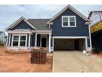 New construction home featuring navy siding, white trim, large garage and neatly stacked brick for finishing the landscape at 771 Old Station Pointe, Angier, NC 27501