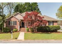 Charming brick home featuring a landscaped front yard, mature trees, and inviting entrance at 8837 Walking Stick Trl, Raleigh, NC 27615