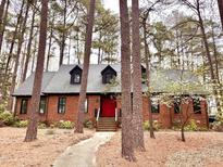Charming brick home with a striking red door nestled among mature trees, offering a blend of privacy and curb appeal at 917 Queensferry Rd, Cary, NC 27511