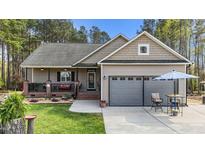 Charming single-story home featuring a cozy front porch, a two-car garage, and beautifully landscaped front yard at 97 Silver Creek Dr, Clayton, NC 27520