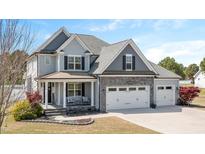 Charming two-story home with gray siding, stone accents, and a well-manicured lawn at 14 E Saddle Ct, Archer Lodge, NC 27527