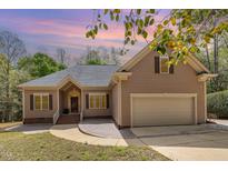 Charming home featuring mature trees, landscaping, and a two-car garage with an inviting front entry and warm facade at 1409 Turner Farms Rd, Garner, NC 27529
