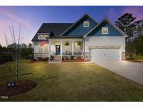 Charming two-story home with a welcoming front porch, attached garage, and manicured lawn at 16 Blue Monarch Ln, Fuquay Varina, NC 27526