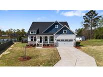 Charming two-story home features a manicured lawn, attached two-car garage, and inviting front porch at 16 Blue Monarch Ln, Fuquay Varina, NC 27526
