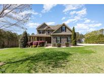 Charming two-story home with stone accents, manicured lawn, and lush landscaping at 3034 E Bay Court, Creedmoor, NC 27522