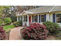 Charming home featuring a bright red front door, classic shutters, and lush landscaping at 6719 Falconbridge Rd, Chapel Hill, NC 27517