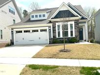Charming home with a two-car garage and stone accents, featuring a well-maintained front yard at 7125 Crested Iris Pl, Durham, NC 27703