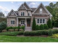 Charming two-story home featuring a stone and siding exterior, well-manicured landscaping, and a welcoming front porch at 7312 Ridgeline Dr, Raleigh, NC 27613