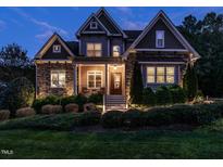 Charming two-story home with stone accents, manicured landscaping, and inviting front porch at dusk at 7312 Ridgeline Dr, Raleigh, NC 27613