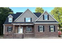 Traditional brick home featuring black shutters, a covered porch, and architectural roof elements at 801 Emmett Ct, Spring Hope, NC 27882