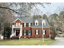 Beautiful two-story brick home featuring a welcoming front porch, manicured lawn, and lush spring foliage at 8508 Kayenta Ct, Wake Forest, NC 27587