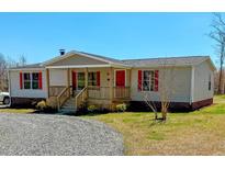 Inviting single-story home with a charming front porch, red accents, and well-maintained landscaping at 210 Holloway Rd, Roxboro, NC 27573