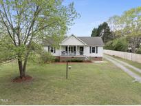 Charming ranch home with a well-manicured lawn, inviting porch, and traditional architectural details at 221 Walkers Way, Willow Springs, NC 27592