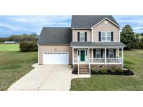 Charming two-story home featuring a cozy front porch, attached garage, and well-manicured lawn at 236 Summer Place Ct, Clayton, NC 27527