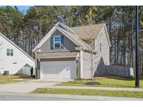 Charming gray home with a two-car garage, a well-manicured lawn, and a backdrop of tall trees providing shade at 250 Hawksbill Dr, Franklinton, NC 27525