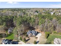 Expansive aerial view of a brick home nestled among trees, featuring a circular driveway at 2514 Mcgowan Ct, Wake Forest, NC 27587