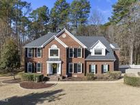 Elegant two-story brick home with a dark roof, black shutters, manicured lawn and mature landscaping at 2514 Mcgowan Ct, Wake Forest, NC 27587