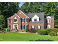 Stately brick home featuring a manicured lawn, mature trees, and a welcoming front entrance with tasteful landscaping at 2514 Mcgowan Ct, Wake Forest, NC 27587