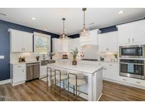 Bright, modern kitchen features white cabinets, stainless steel appliances, and a large island with seating at 332 Tumbling River Dr, Wendell, NC 27591