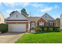 Charming brick home featuring a well-manicured front yard and attached two-car garage, with beautiful lawn at 406 Southshore Pkwy, Durham, NC 27703