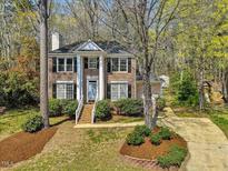 Charming brick home boasts a symmetrical facade with white columns, lush landscaping, and a welcoming entrance at 4818 Glendarion Dr, Durham, NC 27713