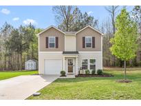 Charming two-story home featuring a well-manicured lawn and inviting facade with a garage and a storage building at 5310 Gannet Ct, Snow Camp, NC 27349