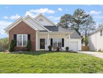 Charming home with a brick accent, covered front porch, and well-maintained lawn at 8701 Neuse Village Ct, Raleigh, NC 27616